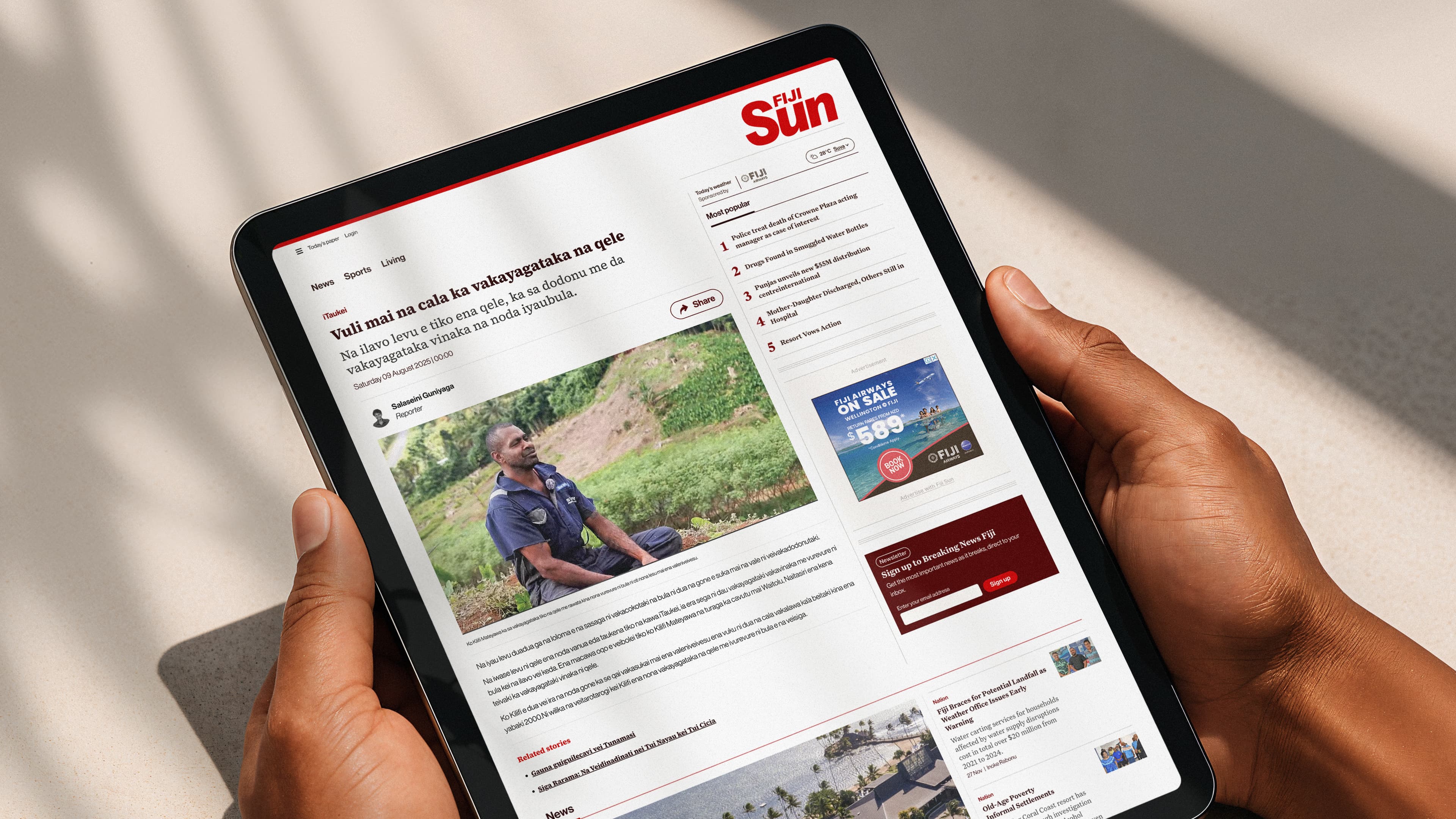 someone holding an ipad with The Fiji sun homepage on the screen 